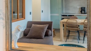 Una habitación con un espejo grande, un sofá, una mesa de comedor con sillas y una zona de cocina.