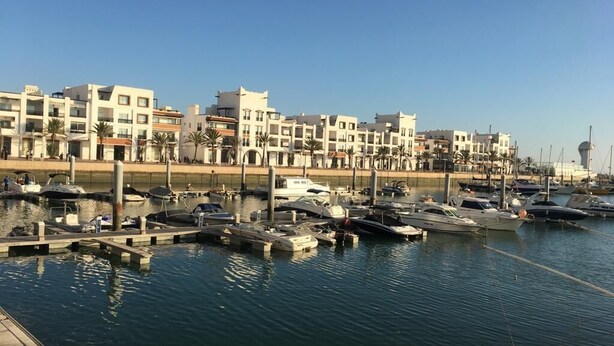 A marina with several yachts docked, surrounded by modern buildings with balconies. - Apartment rental at agadir marina, إجار شقة بمارينا أكادير (Agadir)
