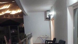 An outdoor seating area with a long bench and chairs, a small cactus garden, and a ceiling light fixture. - Apartment rental at agadir marina, إجار شقة بمارينا أكادير (Agadir)