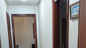 A hallway with a tiled floor, wooden doors, and a ceiling light. - Apartment rental at agadir marina, إجار شقة بمارينا أكادير (Agadir)