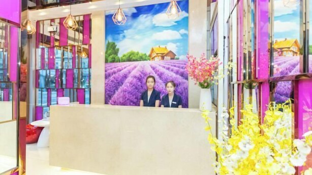A reception area with a mural of a lavender field, a reception desk, and hanging pendant lights. - Liman Hotel (Guangzhou)