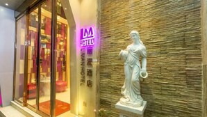 A hotel entrance with a glass facade, a neon sign, and a classical statue. - Liman Hotel (Guangzhou)