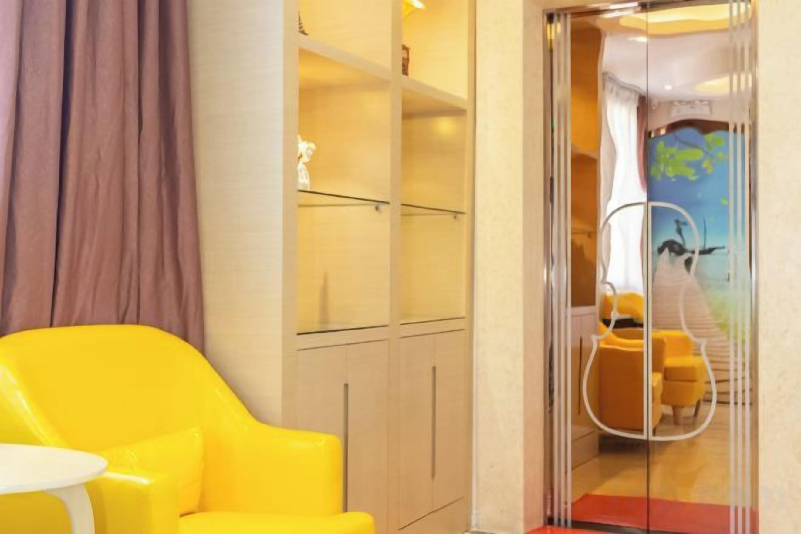 Una habitación con una silla amarilla, una mesita pequeña y un armario con puertas de cristal.