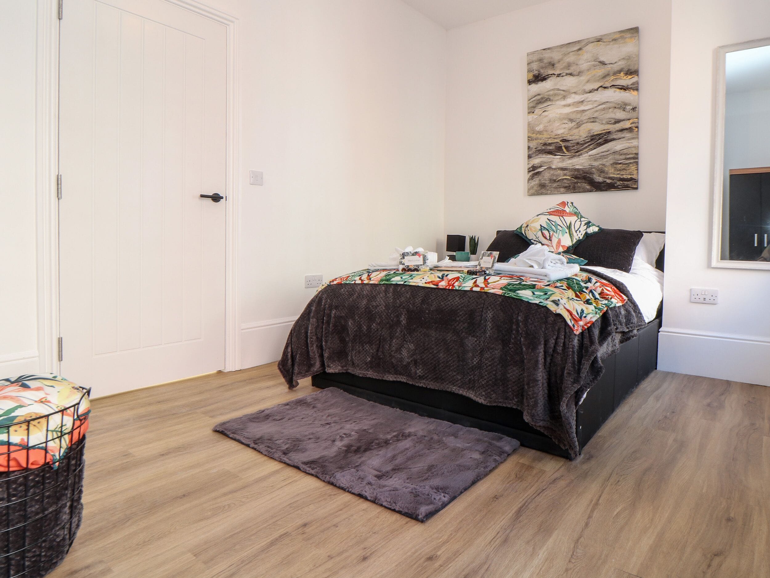 A bedroom with a bed, a nightstand, a wall-mounted artwork, and a window.