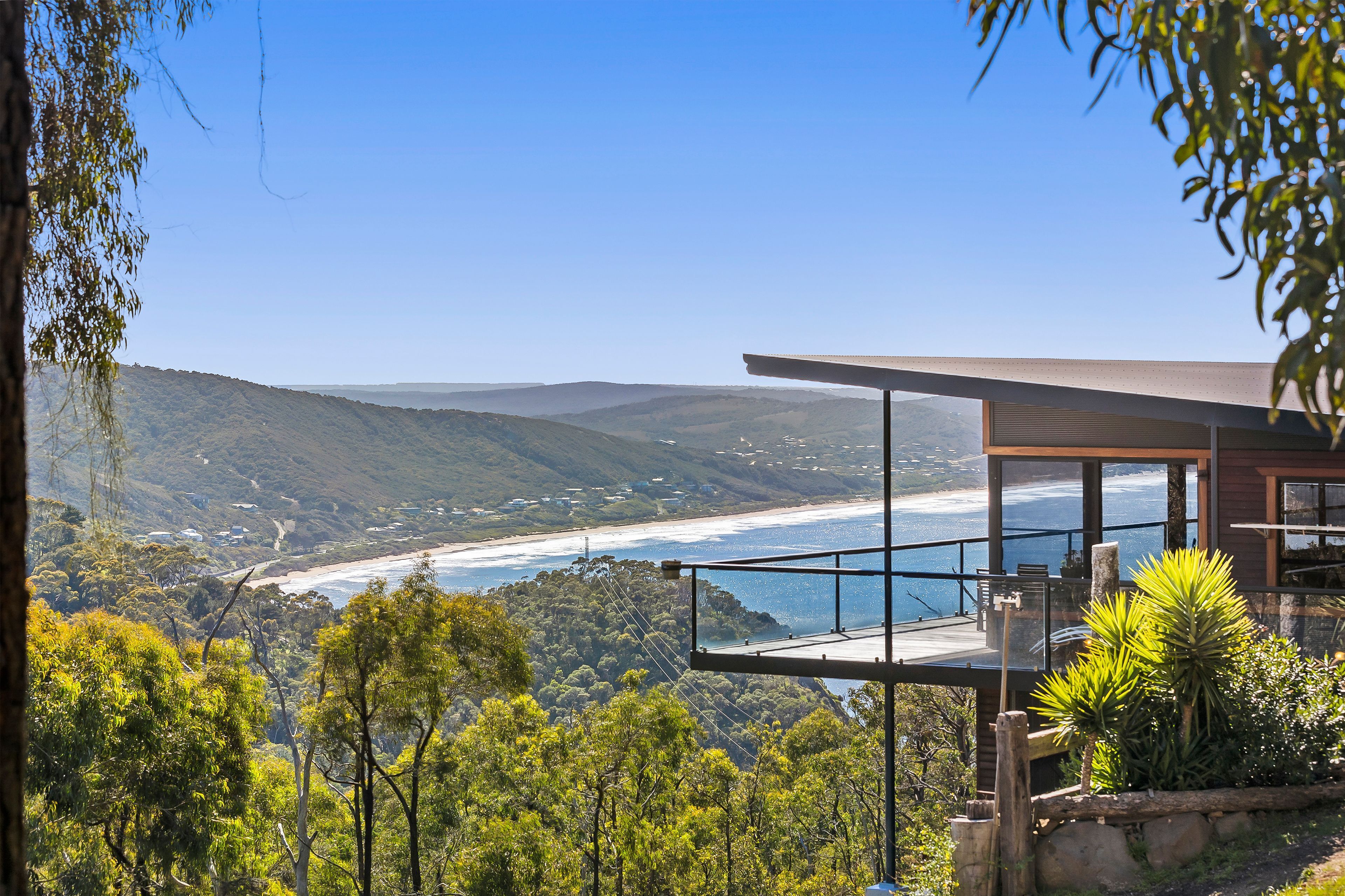 A modern house with a balcony overlooking a coastal landscape.