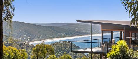 A modern house with a balcony overlooking a coastal landscape.