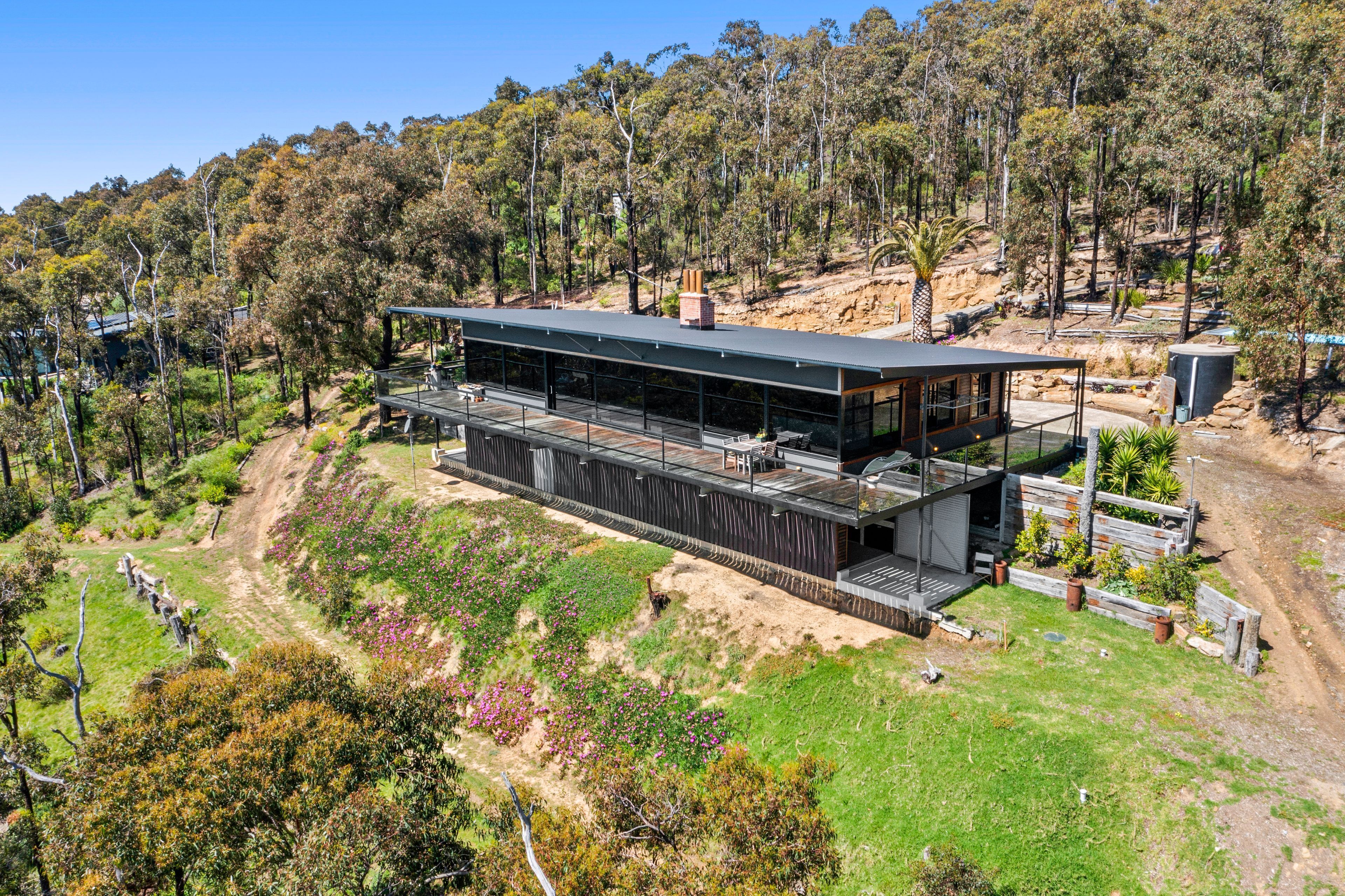 Une maison moderne à deux étages, dotée d’un toit plat, de grandes fenêtres et d’une terrasse.