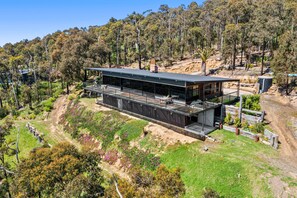 A modern two-story house with a flat roof, large windows, and a deck. - Big Hill Rustic Retreat (Big Hill)