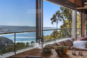A modern interior with a large window offering a scenic view of a valley and hills. - Big Hill Rustic Retreat (Big Hill)