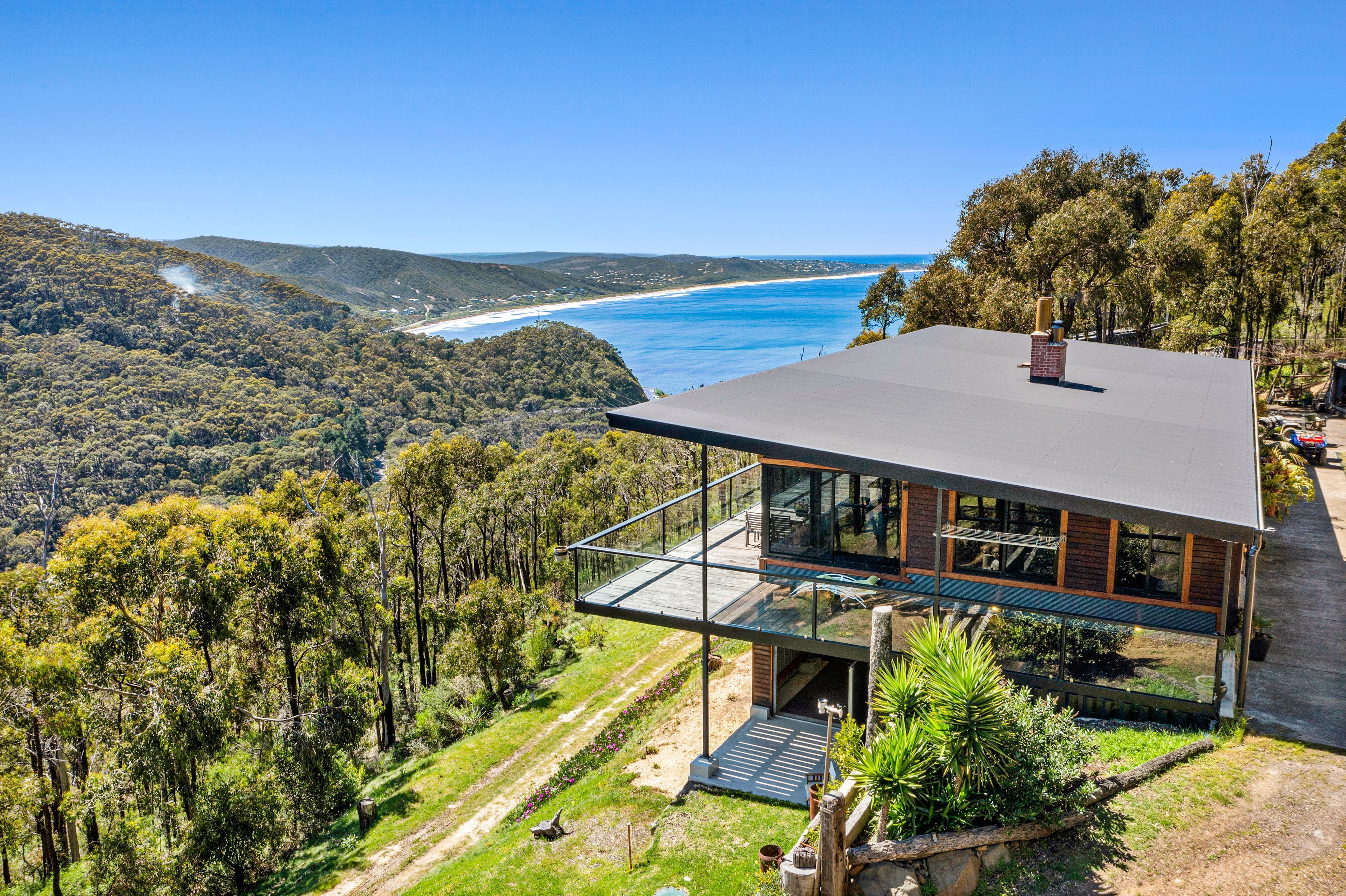 A modern house with a glass balcony overlooking a coastal landscape.