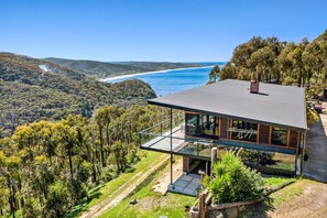 Una casa moderna con balcón de vidrio que da a un paisaje costero.