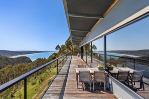 Una terraza de madera con mobiliario exterior con vistas a un paisaje costero.