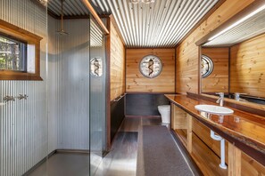 Un baño moderno con paredes de madera, un espejo grande, un lavabo y un inodoro.