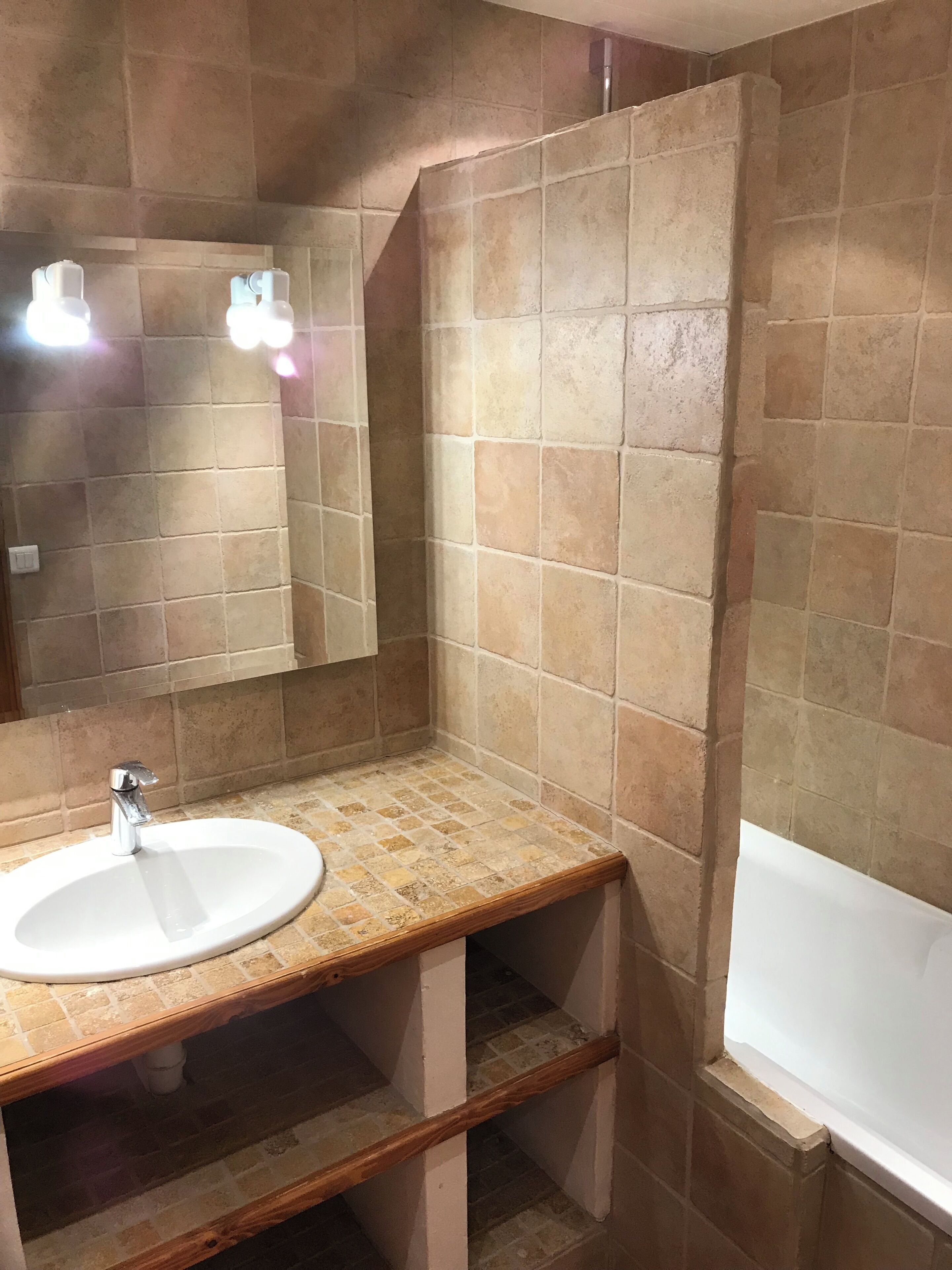 A bathroom with a sink, mirror, and bathtub.