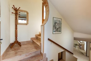 A staircase with a wooden coat rack, a framed picture, and a marble floor.