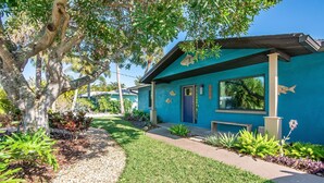 A house with a blue exterior, a front yard with a tree, and a pathway leading to the entrance.