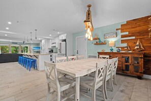 Una cocina moderna con armarios blancos, una mesa de comedor de madera y taburetes de bar azules.