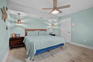 Un dormitorio con cama, mesitas de noche, ventilador de techo y una puerta.