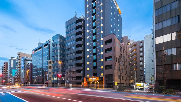A modern hotel with multiple floors, a prominent sign, and a busy street with traffic lights. - APA Hotel Asakusa Kuramae Kita (Tokyo)