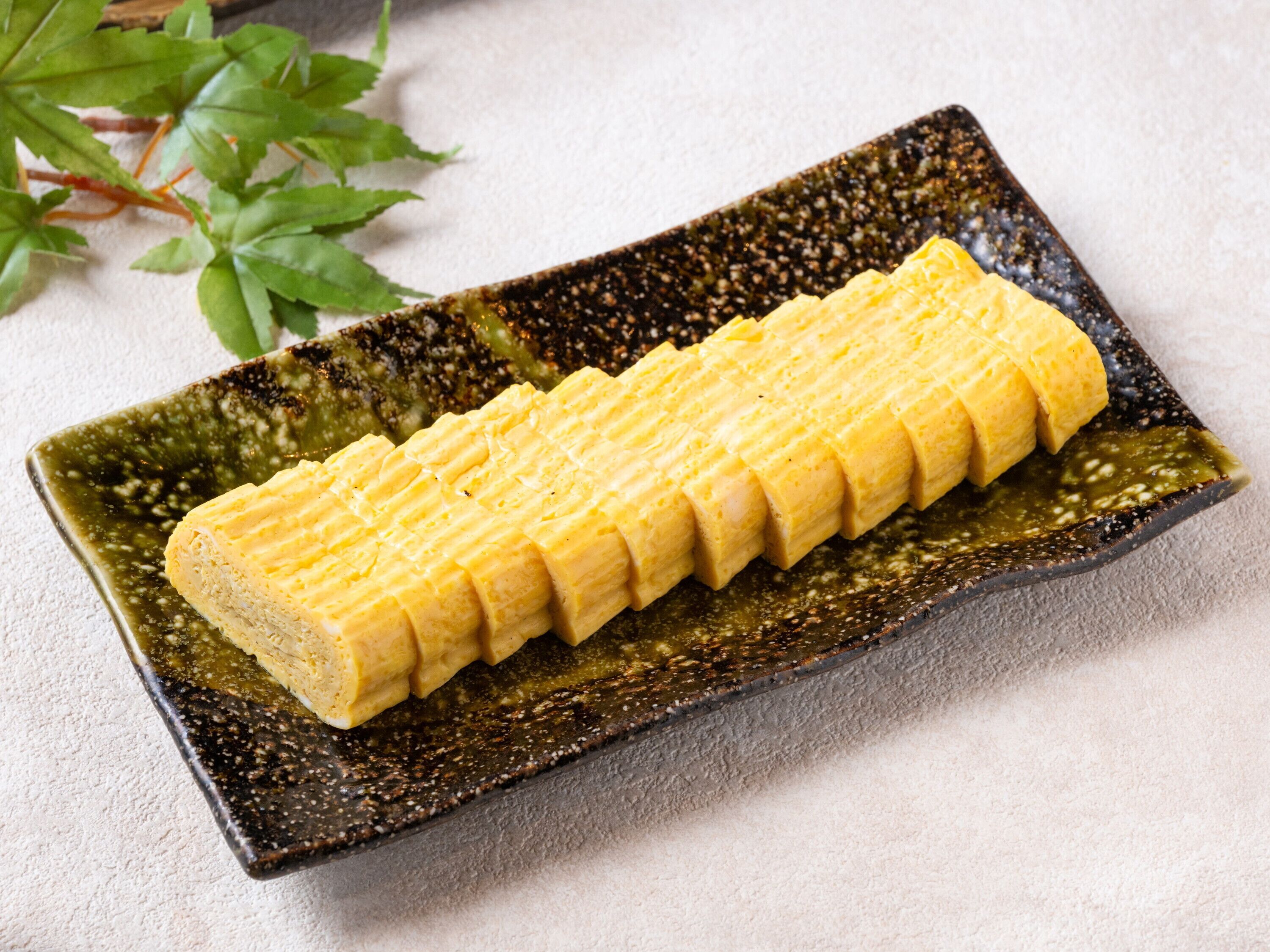 A rectangular plate with a textured pattern, containing a neatly arranged yellow food item.