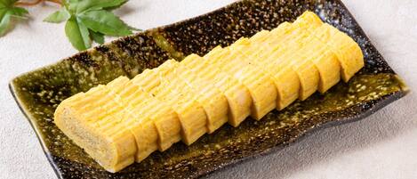 A rectangular plate with a textured pattern, containing a neatly arranged yellow food item.