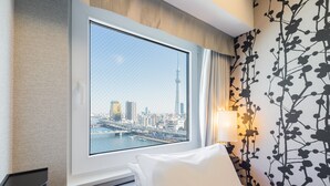 A hotel room with a large window offering a cityscape view, a bed with white bedding, and a wall with a black floral pattern. - APA Hotel Asakusa Kuramae Kita (Tokyo)