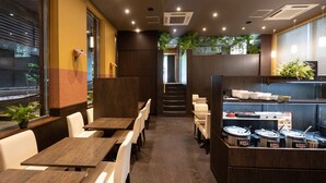 A restaurant interior with wooden tables and chairs, a counter with dishes, and a staircase leading to an upper level. - APA Hotel Asakusa Kuramae Kita (Tokyo)