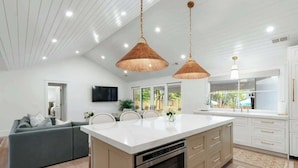 Una cucina moderna con una grande isola, illuminazione a sospensione e vista sull'esterno.