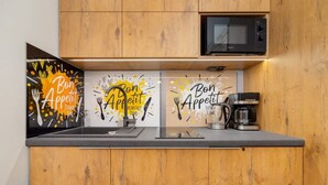 A kitchen with wooden cabinets, a microwave, a coffee maker, and three framed signs with 'Bon Appetit' text. - Comfortable Studio in Cracow | Place to Work | Close to Market Square (Kraków)