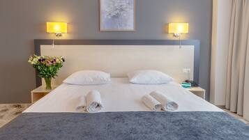 Una habitación de hotel con una cama grande, dos lámparas de noche, un jarrón de flores y un cuadro en la pared.