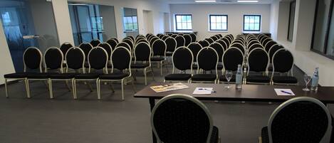 A conference room with rows of chairs, tables, and a large window.