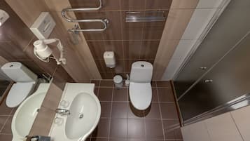 A modern bathroom with a bathtub, two toilets, a sink, and a shower.