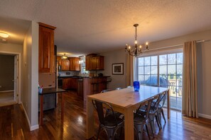 A spacious kitchen with wooden cabinets, a dining table with chairs, and a chandelier. - Petes Alpine Retreat - pet friendly Seven Devils home close to ziplining, snow tubing (Seven Devils)