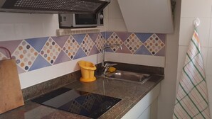 Una cocina con microondas, lavamanos y un salpicadero de colores.