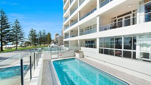 Un hotel moderno con piscina, diversi balconi e vista sulla spiaggia.