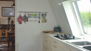 Et køkken med hvide skabe, et vindue og en hængende lampe.