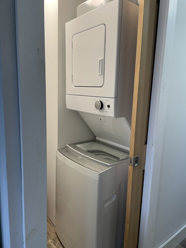 Een compact, wit was- en droogcombinatie, bevestigd aan de muur, met een bedieningspaneel en een klein raampje.