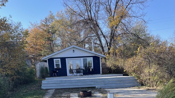 A wooden deck leading to a house with a porch and outdoor seating.
