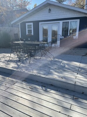 A house with a patio featuring a metal table and chairs, a small deck, and a garage. - Very quaint, small Cottage on historic Idlewild lake (Idlewild)