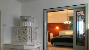 A bedroom with a bed, a white decorative corner piece, a fluffy rug, and a door leading to another room.
