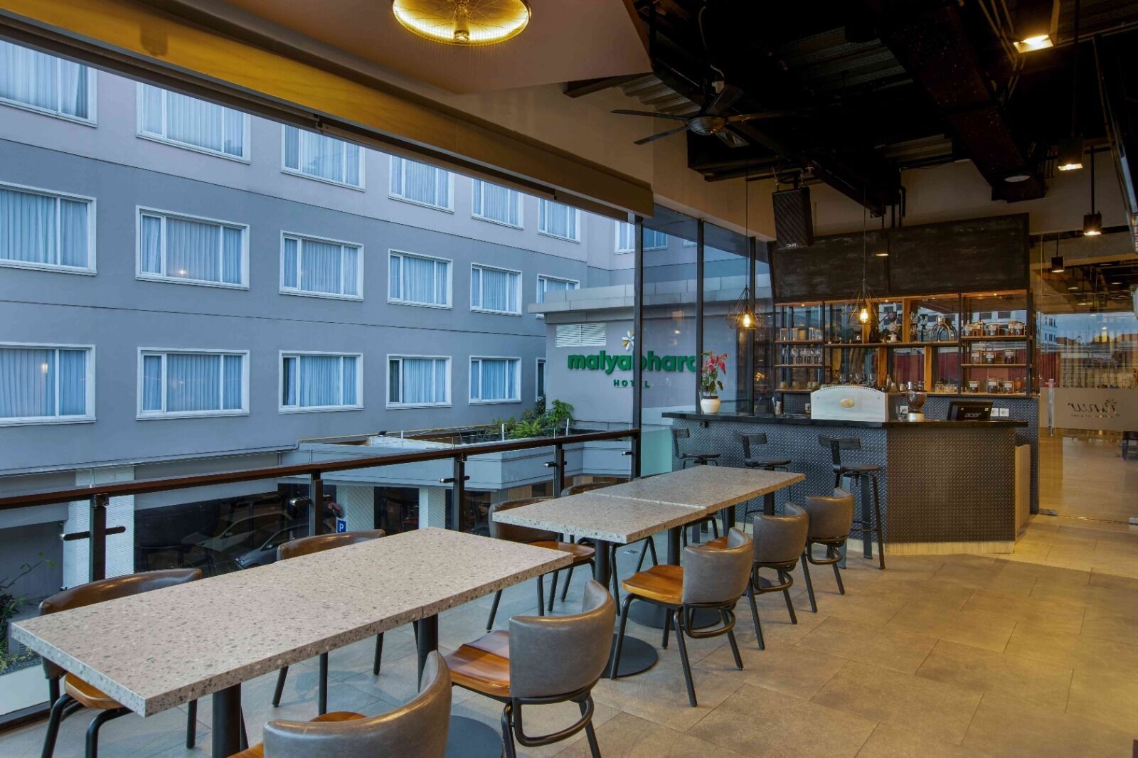 A modern hotel lobby with a bar area, seating arrangements, and a view of the building's exterior.