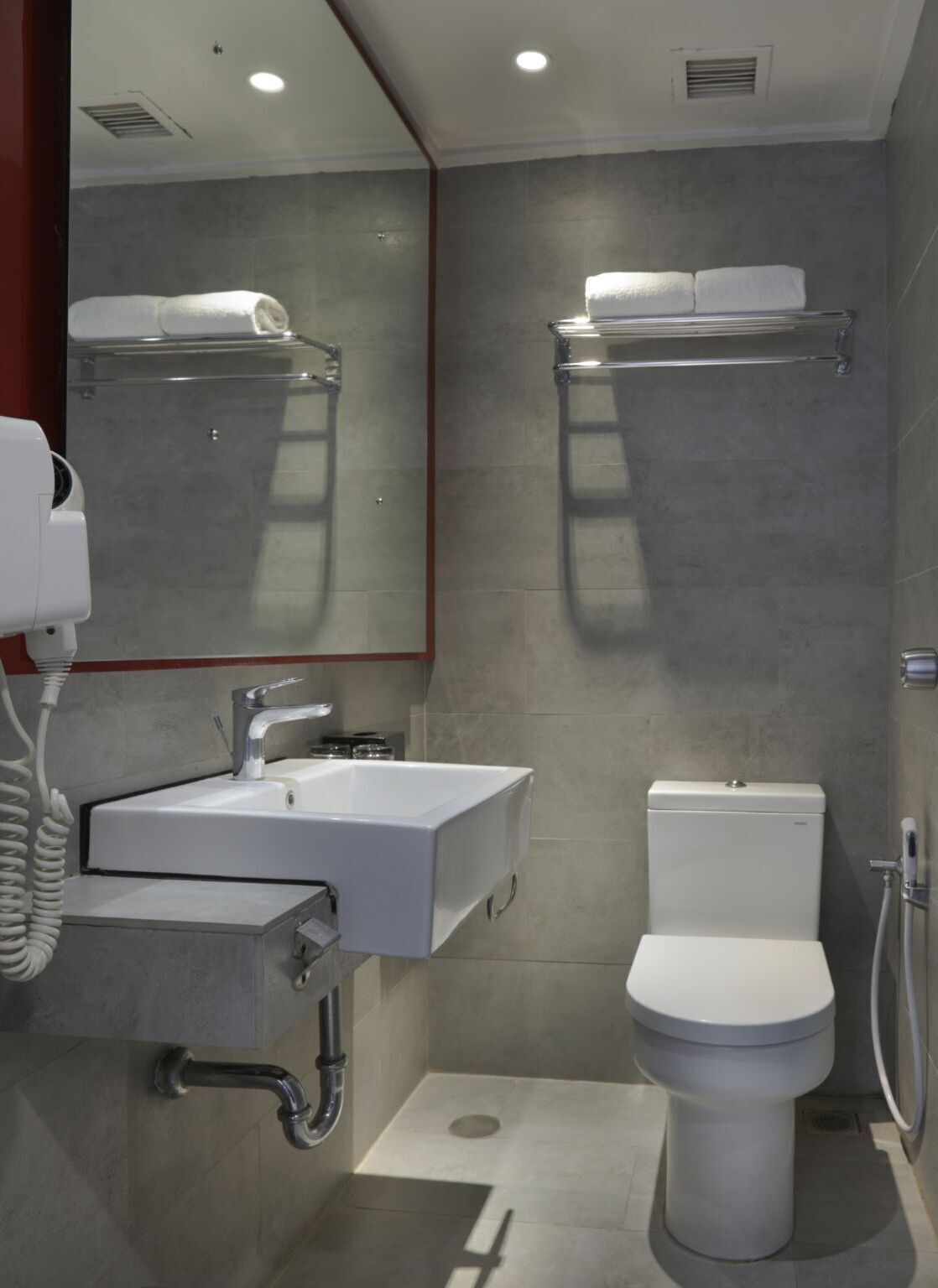 Une salle de bain moderne avec un lavabo blanc, des toilettes et un espace douche.