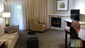 A living room with a sofa, armchair, ottoman, fireplace, and a TV. - Charming Copeland 1-bed Condo + patio + hot tub (Oro)