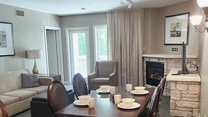 A modern living room with a dining area, a fireplace, and a large window. - Charming Copeland 1-bed Condo + patio + hot tub (Oro)