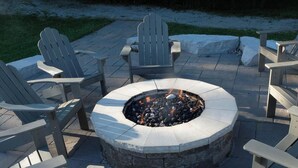 A circular fire pit surrounded by Adirondack chairs on a stone patio. - Charming Copeland 1-bed Condo + patio + hot tub (Oro)