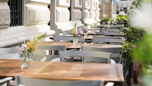 An outdoor cafe with tables and chairs, decorated with flowers. - Almanac Palais Vienna (Vienna)