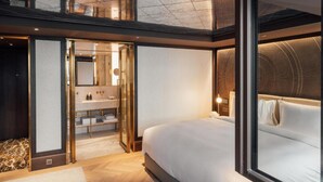 A modern hotel room with a large bed, a glass-enclosed bathroom, and a view of the cityscape. - Almanac Palais Vienna (Vienna)