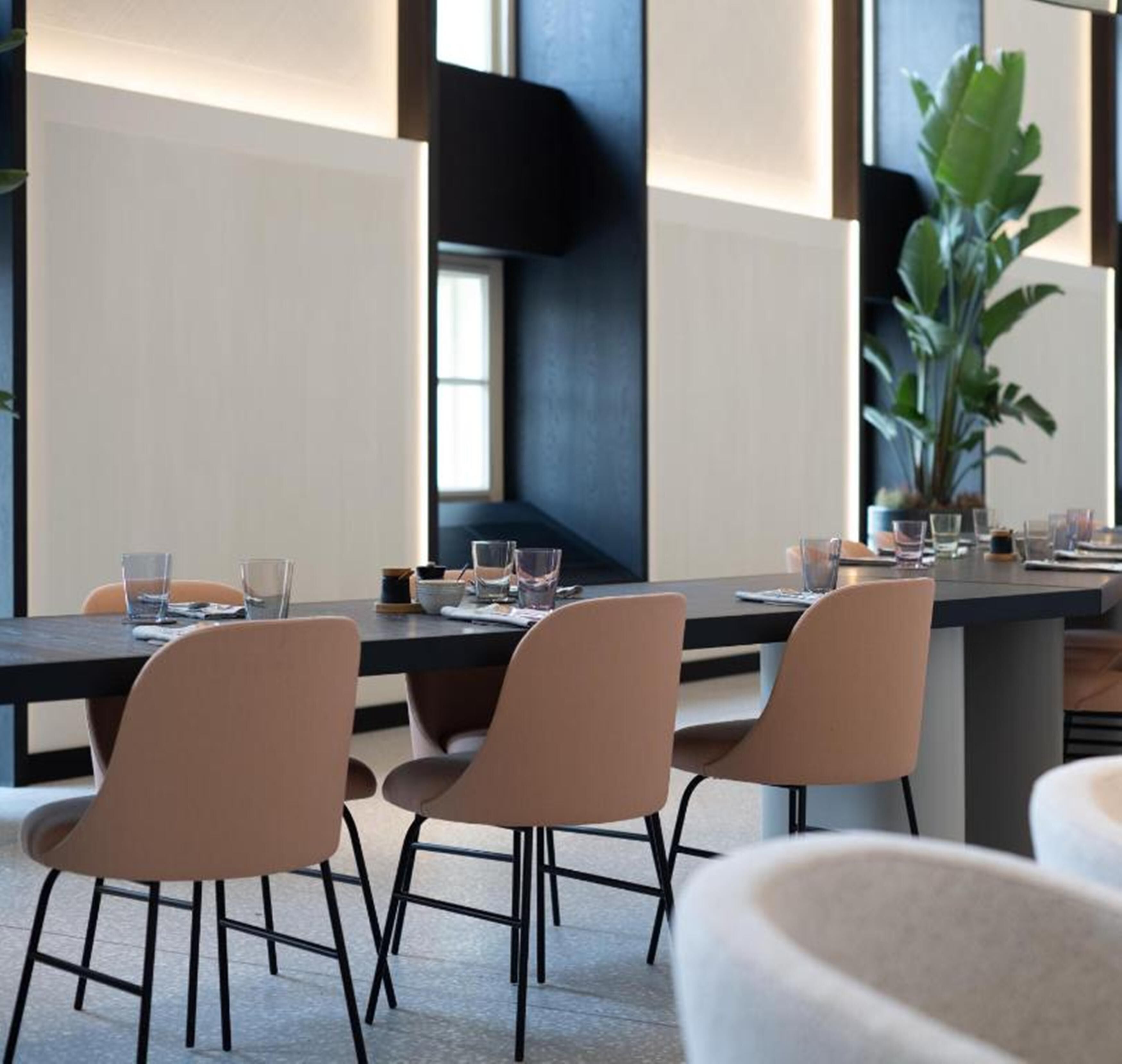 Een moderne vergaderruimte met een lange tafel, vier stoelen en een potplant.