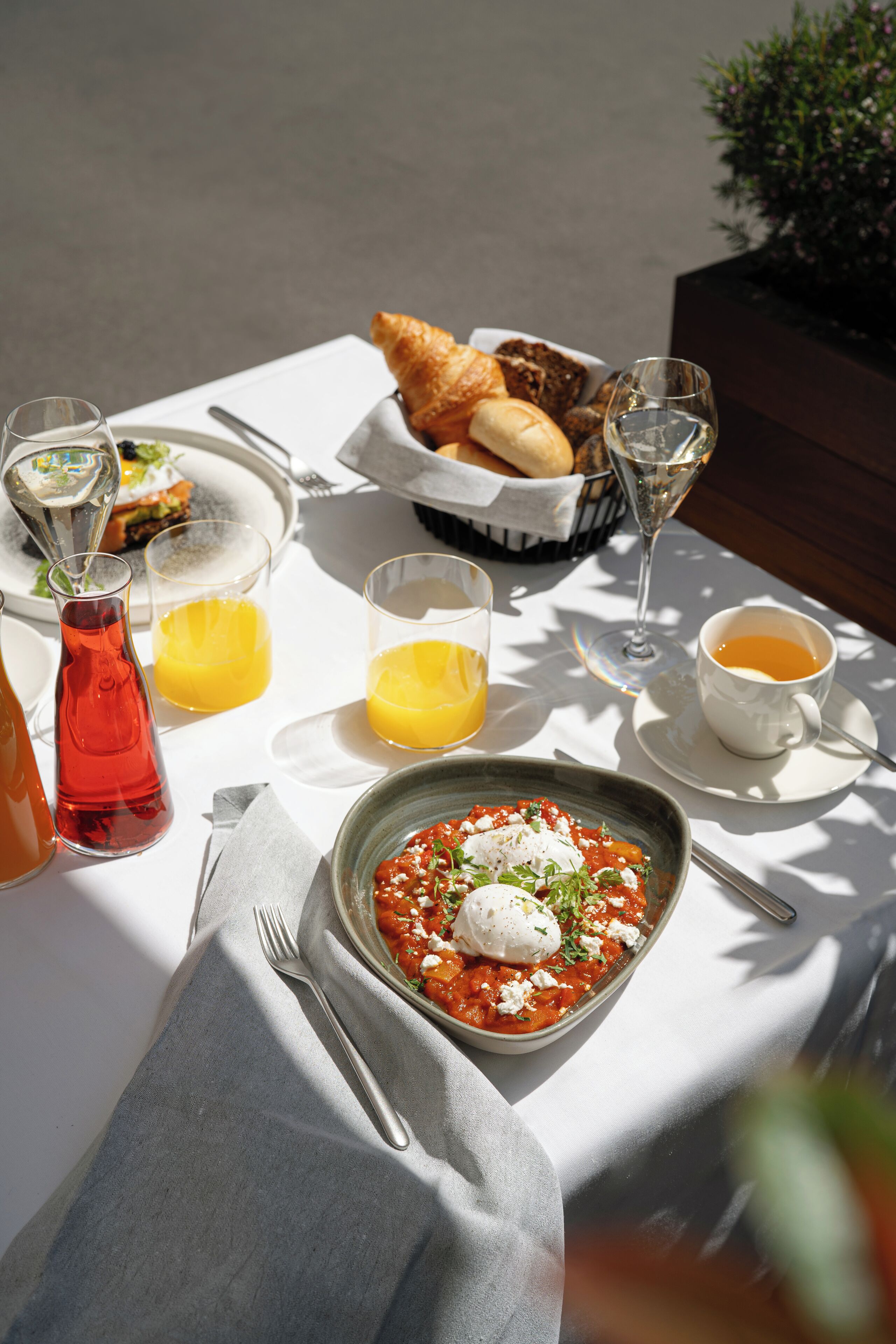 A table set with a meal, including a bowl of pasta, bread, and drinks.