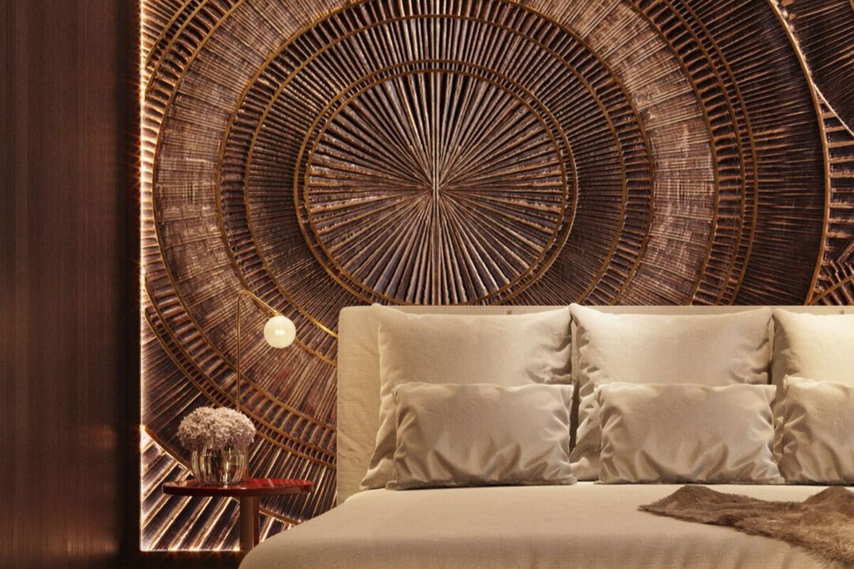 A bed with a circular wall design, a bedside table with a lamp, and a vase of flowers.